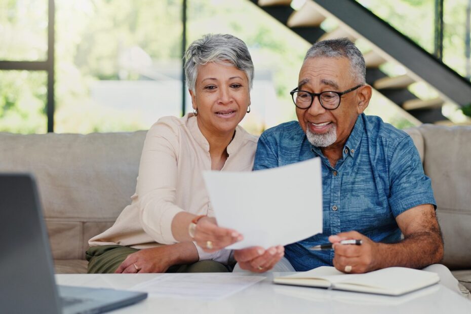Couple de retraités examinant des documents liés à un investissement locatif autour d’une table.